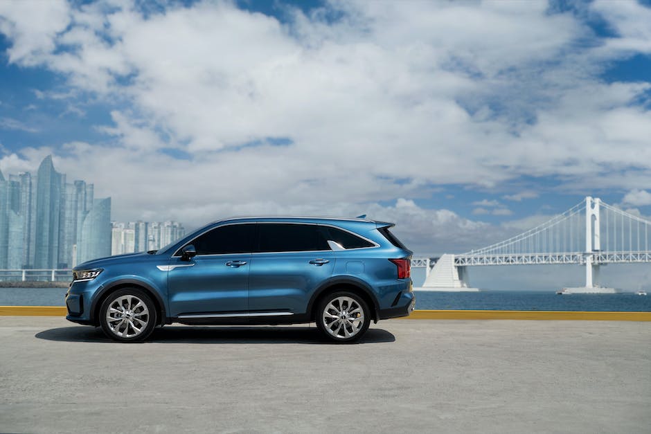 A blue Kia Sorento parked on a street with trees in the background. The car has a sleek design with a chrome grille and angular headlights.