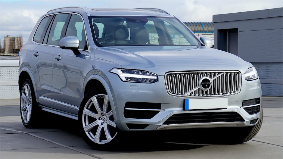 A picture of a silver Volvo XC90 driving down a palm tree-lined road, highlighting the car's luxury and versatility.